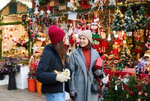two ladies shopping and talking at holiday market