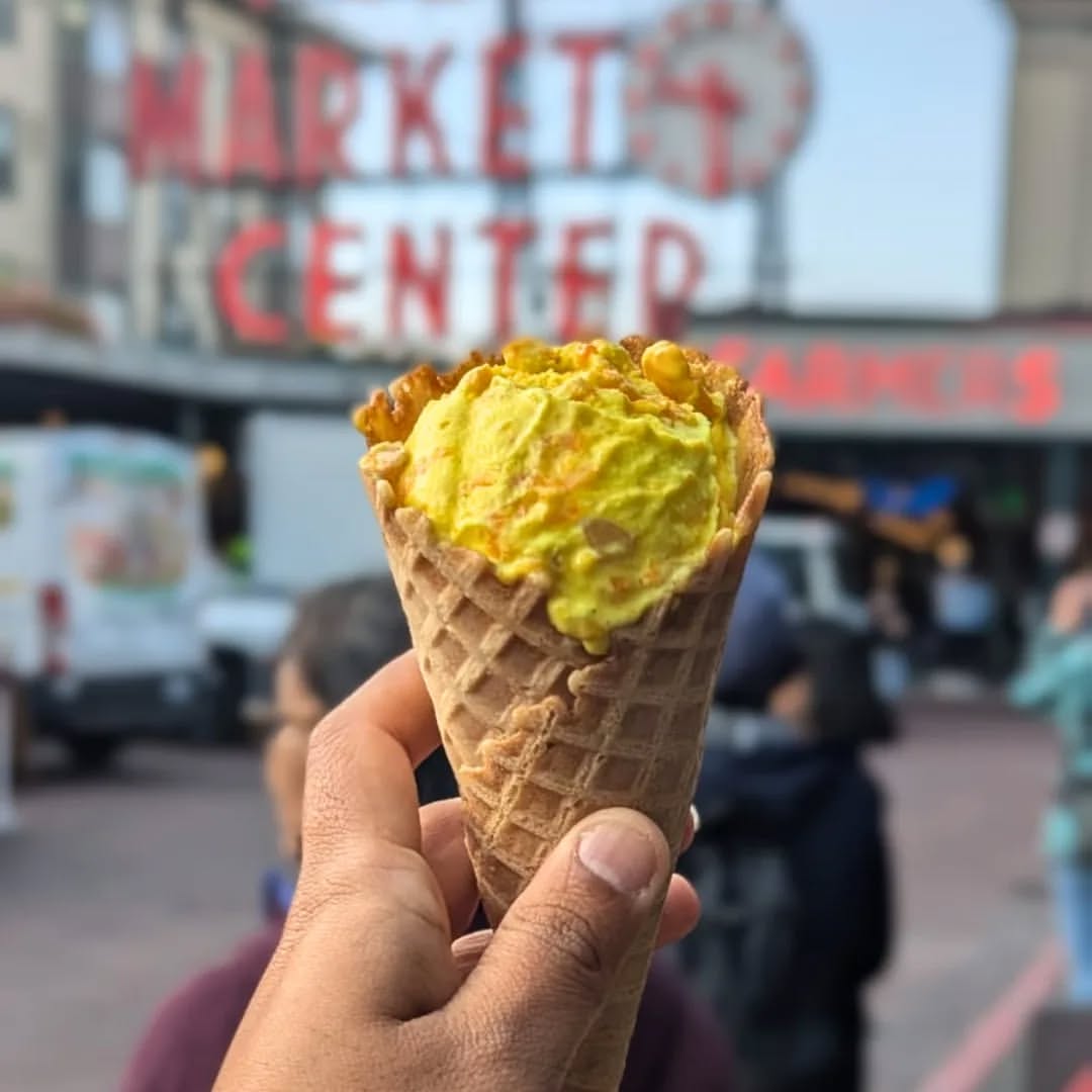Ice cream cone held in front of Pike Place Market sign in Seattle