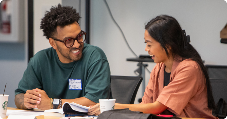 Two young entrepreneurs chatting and reviewing documents in a class. 