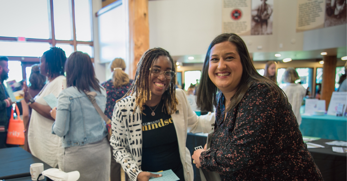 Two women stopping to pose and smile at the busy Celebrating Dreams 2024 event