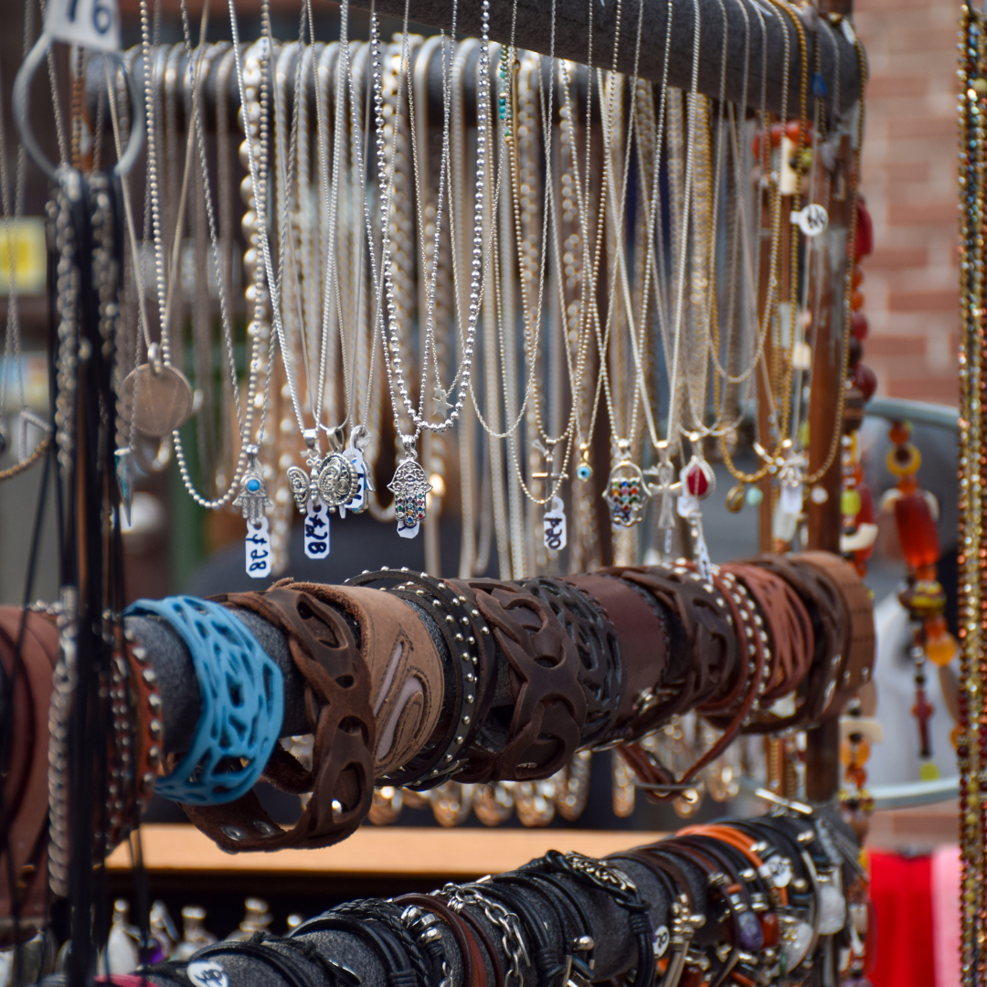 Close-up of necklaces, bracelets, and leather wristbands displayed at a vendor booth.